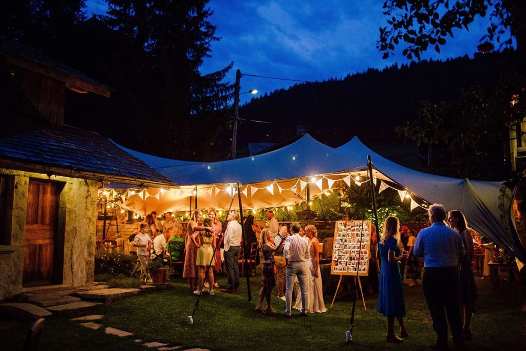 guests enjoy outdoor party in the evening at unique wedding venue in the alps