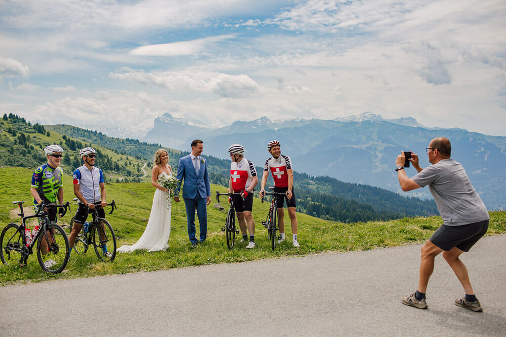 Newly weds pose for photo with cyclists atop an Alpine mountain pass